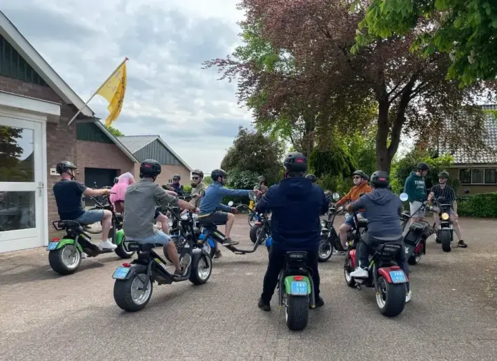 Groep collega's met helmen op e-choppers bij de start van een personeelsuitje nabij Enschede