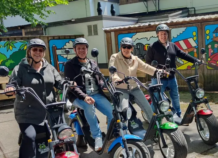 Vier collega's met helmen op kleurrijke e-choppers tijdens een personeelsuitje nabij Hengelo