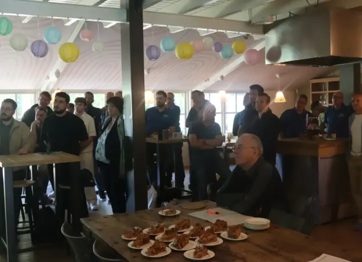 Groep collega's in een sfeervol café met borden taart op tafel tijdens een personeelsuitje nabij Hengelo